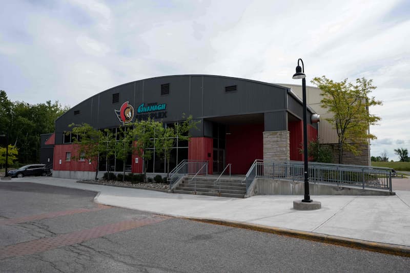Exterior view of a community recreation center with a red and gray facade, stairs, and ramp at the entrance.